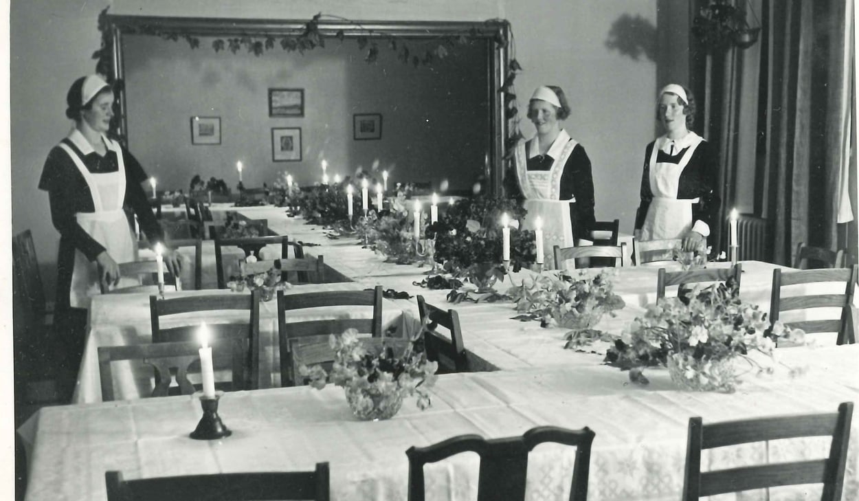 Julbord i sköterskornas dåvarande matsal Bollnäs lasarett. Dukat bord. Tre sköterskor ses stående intill bordet.