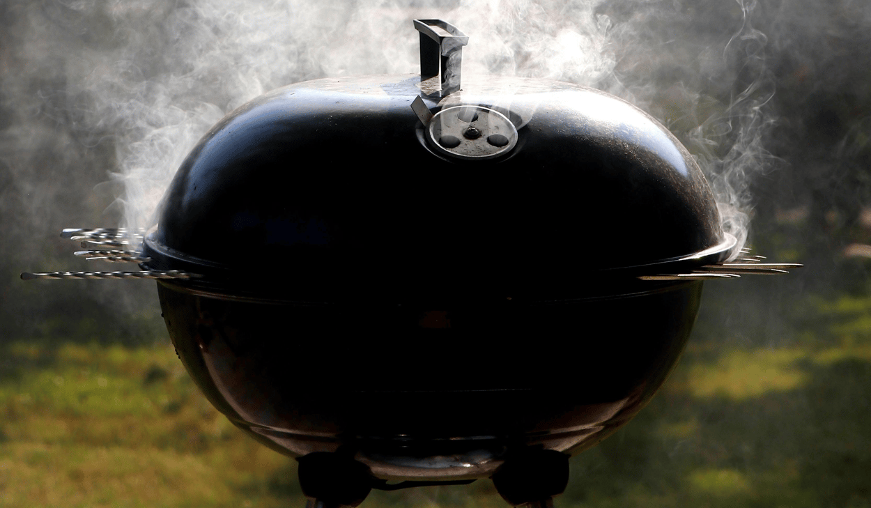 En kolgrill med rök som kommer ut ur den.