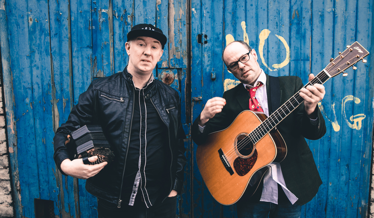 Två män som står bredvid varandra med gitarrer i händerna.
