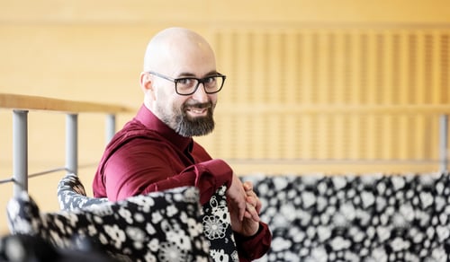 En man med skalligt huvud sitter i en soffa.