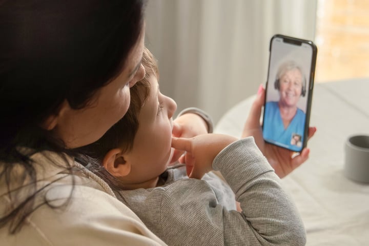 Barn som sitter i kvinnas famn. Pratar med Min vård Gävleborg i telefon.